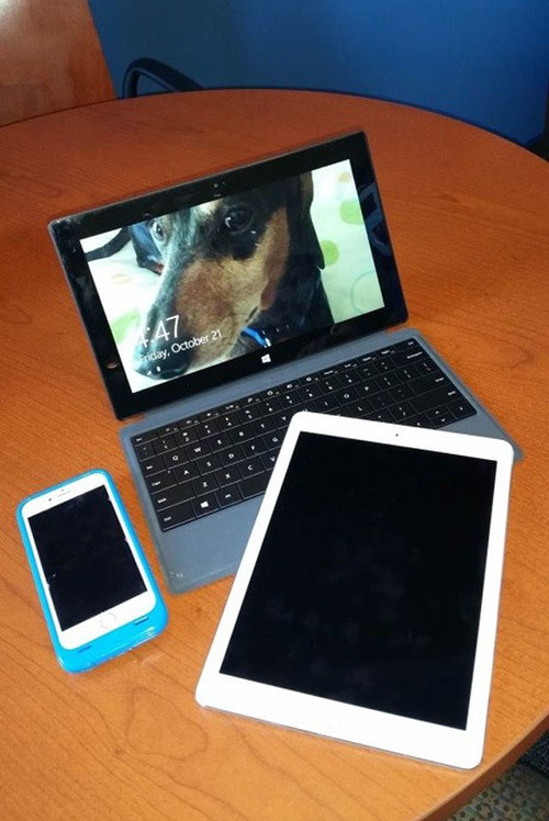 A  laptop, tablet and cellphone on a round wooden table. This shows the need for websites to respond correctly on different devices.